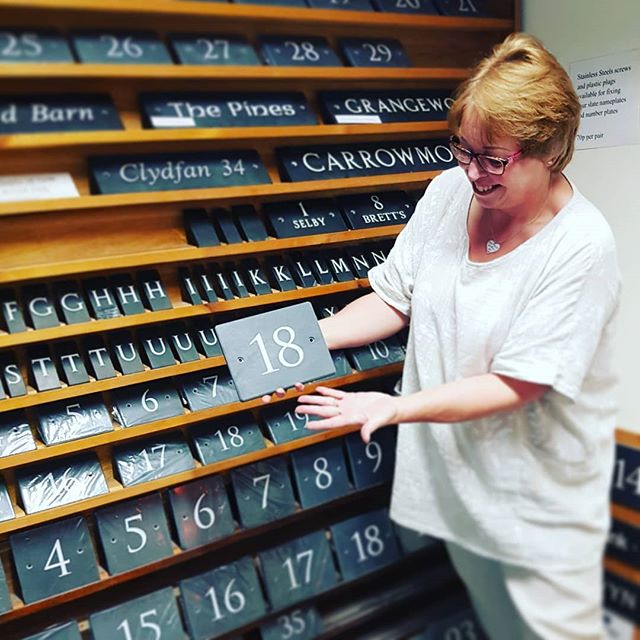 Our Sue, proudly Showcasing our Welsh Slate House Number Signs. Behind her a range of Example Name House Signs and Number House Signs.