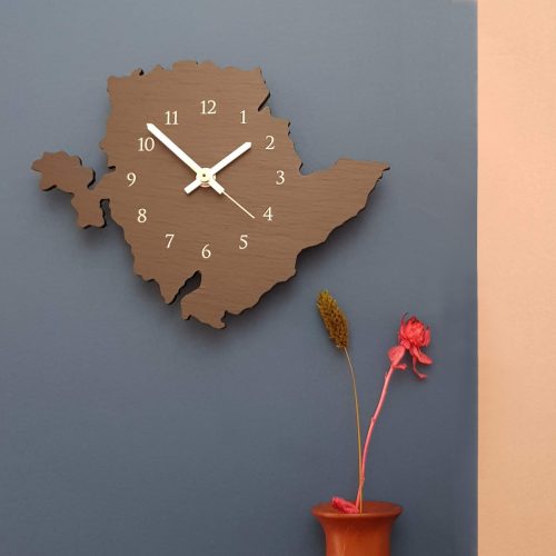 Anglesey Shaped Wall Clock with Arabic dial printed white, placed on wall - by Inigo Jones Slate Works